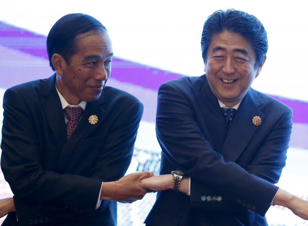 Indonesia's President Widodo links hands with Japan's PM Abe during the 27th ASEAN summit in Kuala Lumpur