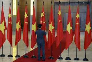 A Vietnamese protocol officer arranges Chinese and Vietnamese flags before the arrival of Chinese President Xi Jinping at the Parliament House in Hanoi
