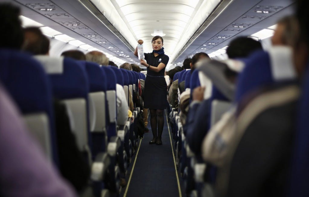 Flight attendants holding up safety information cards and demonstrating safety procedures in the aisle. ｜Photo Credit: REUTERS
