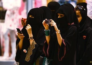 Veiled Saudi women take photos of their children during a ceremony to celebrate Saudi Arabia's Independence Day in Riyadh