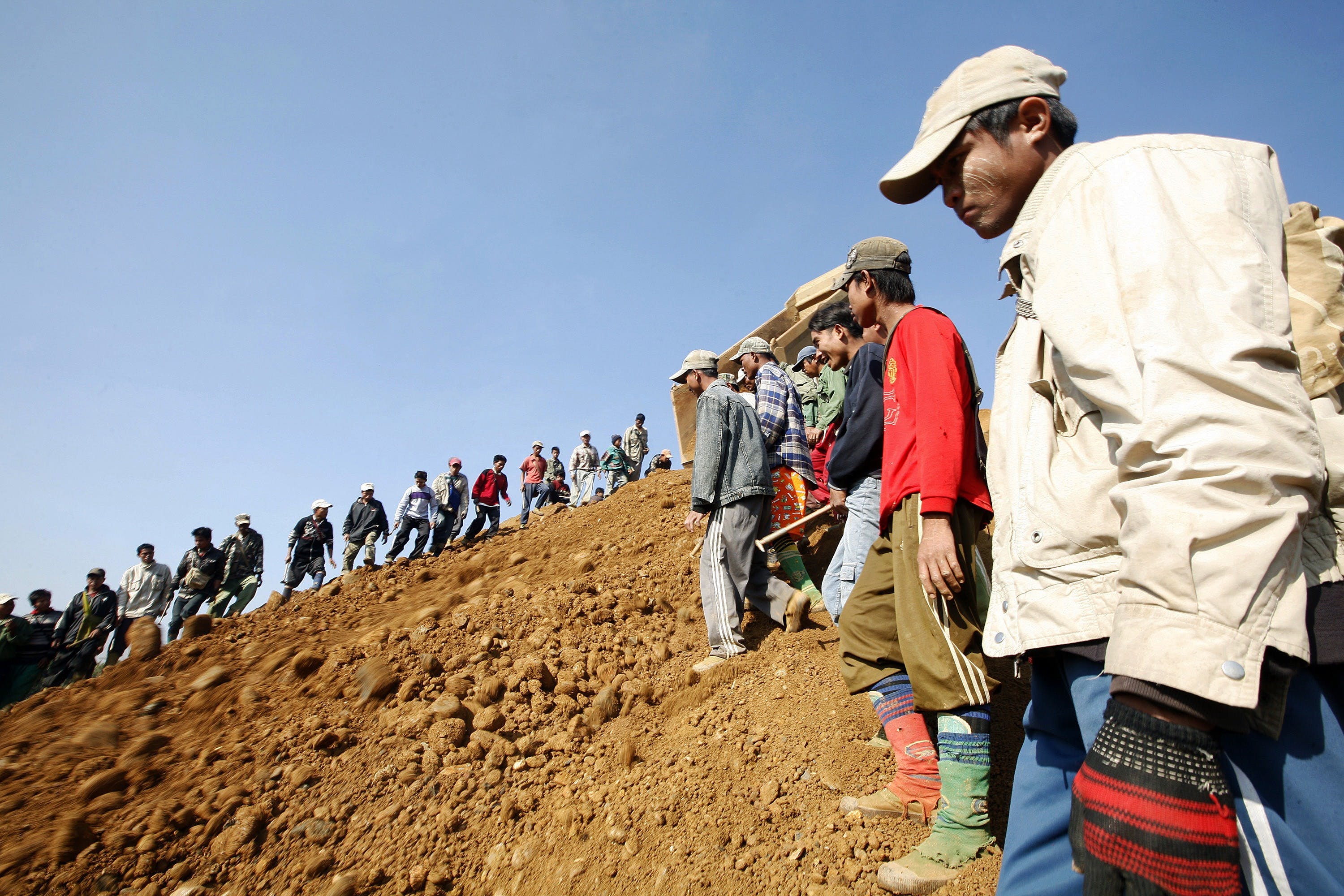 People look for precious stones in the mine dump piled by major mining companies at a jade mine in Pharkant township