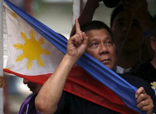 Presidential candidate Rodrigo "Digong" Duterte holds a national flag during election campaigning for May 2016 national elections in Malabon, Metro Manila