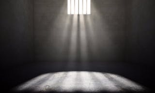 監獄＿Interior of a prison cell with light shining through a barred window