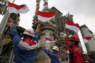 Pertamina employees wave Indonesian flags during a visit by the company's CEO Dwi Soetjipto and Indonesia's Vice-President Jusuf Kalla to the refinery unit IV in Cilicap, Central Java, Indonesia