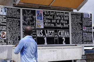 A man reads a board extolling China's contribution to the fight against Ebola, in Monrovia
