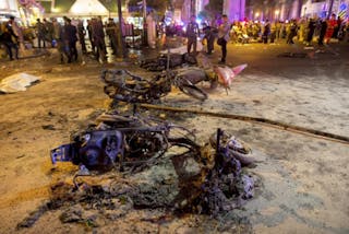 Wreckage of motorcycles are seen as security forces and emergency workers gather at the scene of a blast in central Bangkok