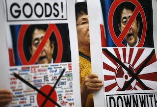 A woman holds a banner depicting Japanese Prime Minister Shinzo Abe during an anti-Japan rally on the occasion of the 70th anniversary of liberation from Japan's 1910-45 colonial rule, on Liberation D