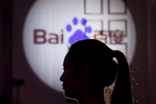 A woman is silhouetted against the Baidu logo at a new product launch from Baidu, in Shanghai, China