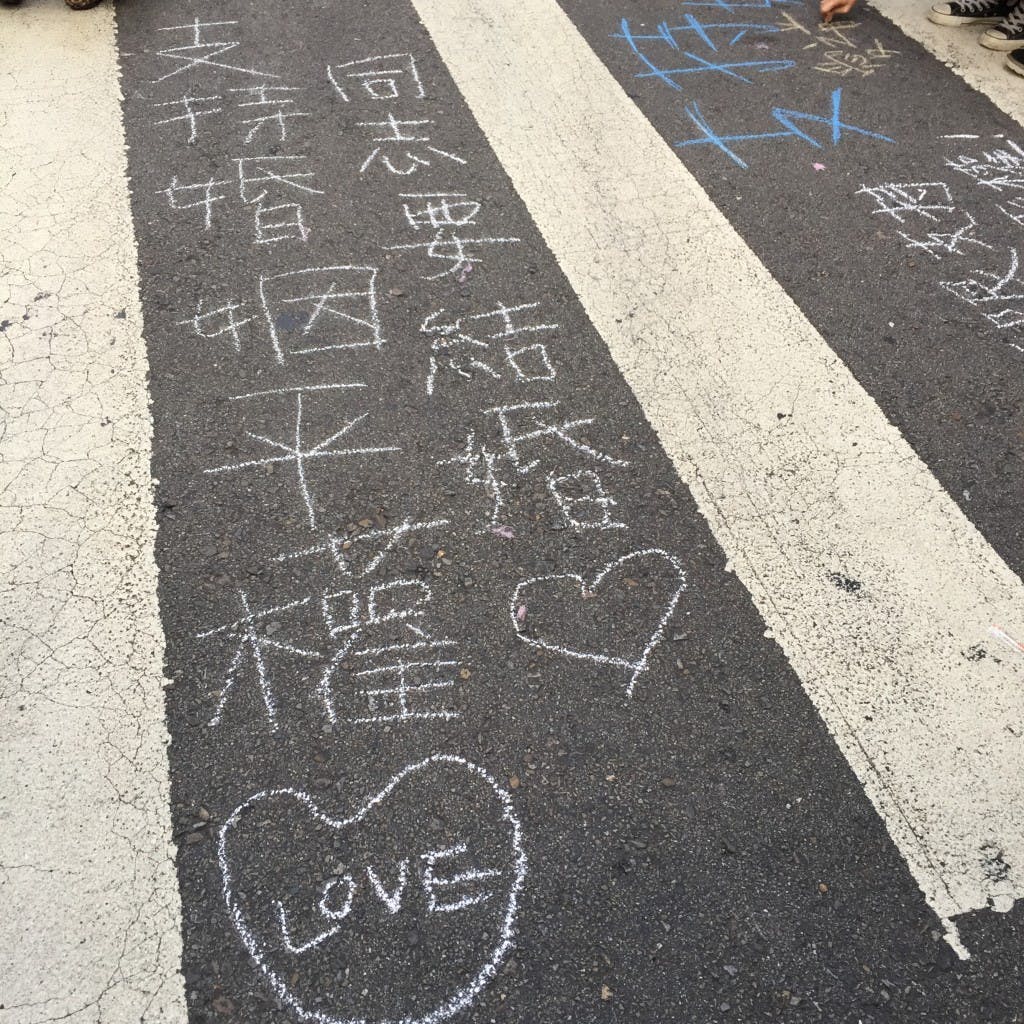 伴侶盟去年在立法院旁舉辦「彩虹圍城」活動，參與者在地上彩繪標語。Photo Credit：陳沂庭 