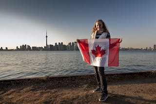 Young woman waving a Canadian flag on Algonquin Island, one of the Toronto Islands, Toronto, Ontario