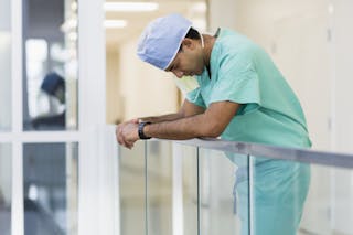 Surgeon leaning on handrail in corridor
