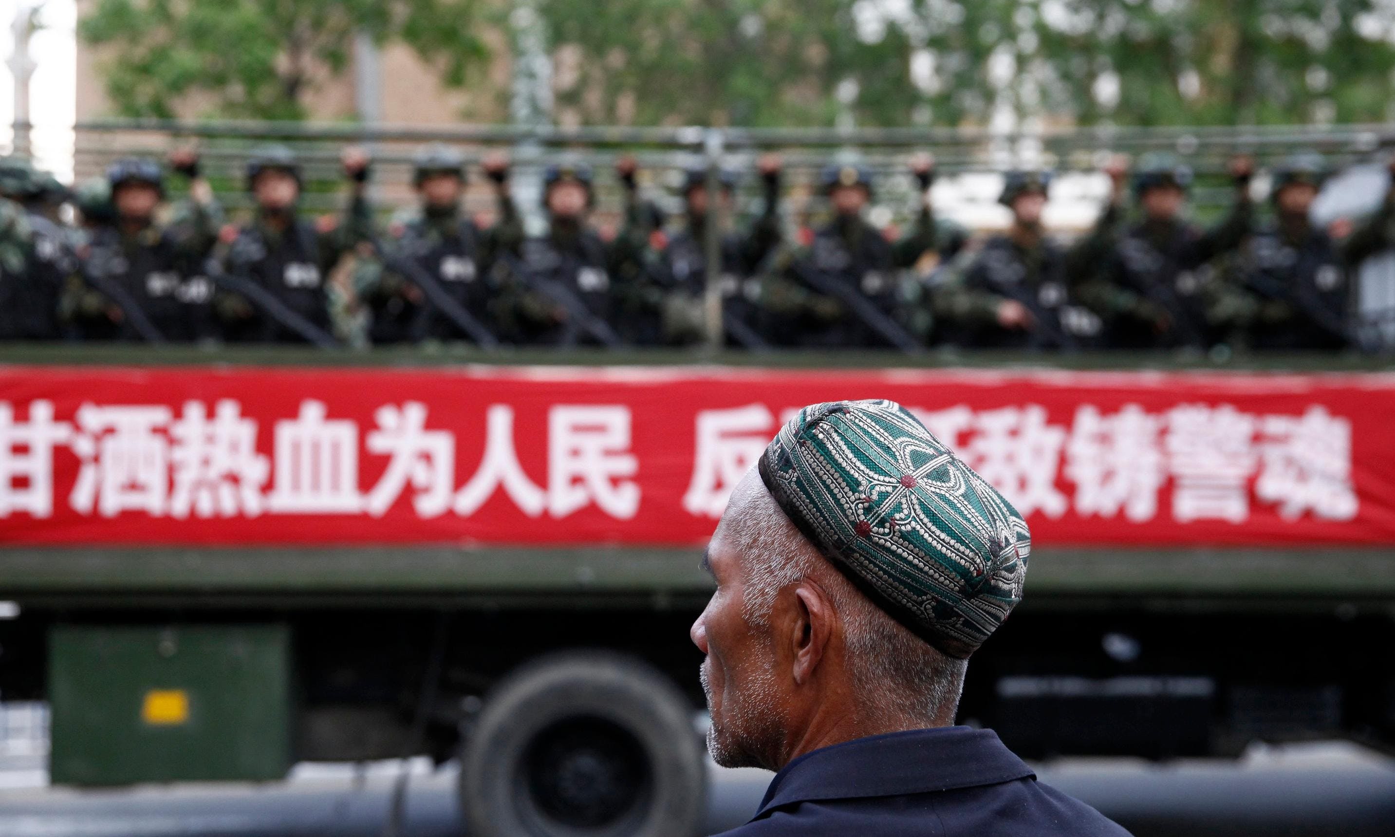 新疆＿維吾爾＿A_Uighur_man_looks_on_as_a_truck_